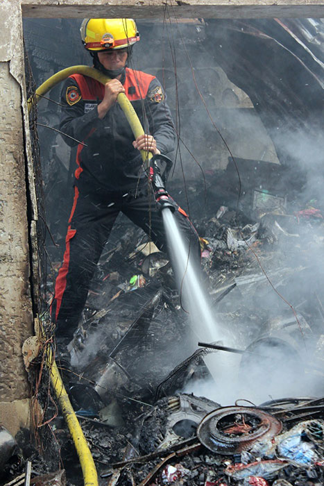 EXTINGUISH. A fireman snuffs out the embers at the Kaking department store on Osmeña St. near Cogon market that was destroyed by a 19-hour fire that started on Sunday afternoon until yesterday morning. (PHOTO BY NITZ ARANCON)