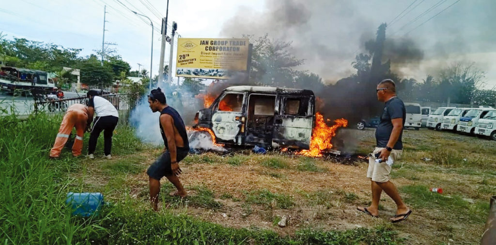 A group of men flank a mini-van that caught fire while on display at the Jan Group Trade Corp. property in Molugan, El Salvador in Misamis Oriental, on Tuesday morning. (photo by Nitz Arancon)